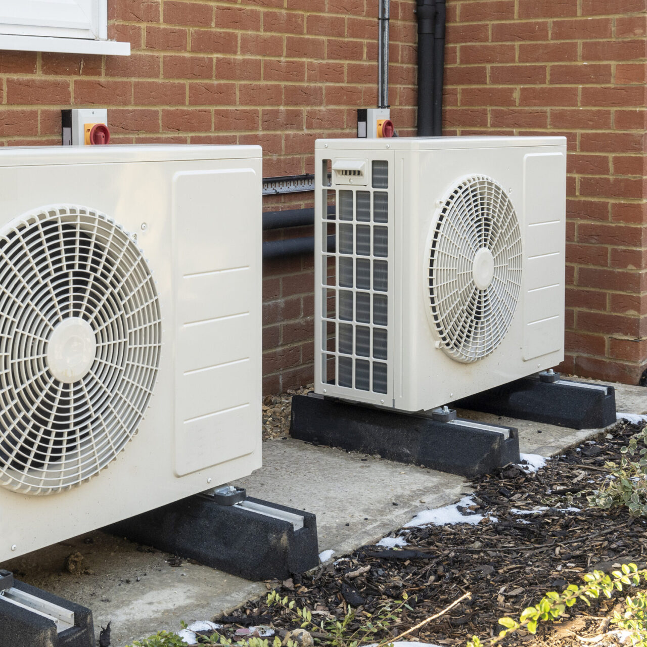 Two air source heat pumps installed on the exterior of a modern house